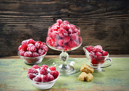 Red frozen raspberries in a glass cup on a wooden tableの写真素材