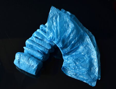 Coronavirus concept.Medical blue disposable shoe covers on black background. Hygiene rules during the coronavirus epidemic.の写真素材