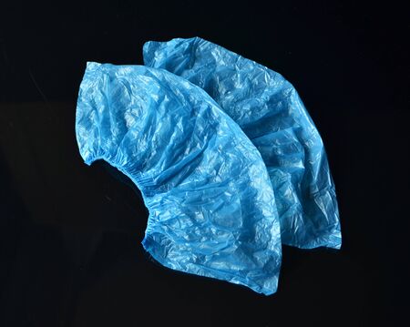 Coronavirus concept.Medical blue disposable shoe covers on black background. Hygiene rules during the coronavirus epidemic.の写真素材