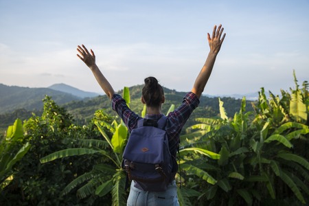 Hipster young girl with backpack enjoying sunset on peak mountain. Tourist traveler on background valley landscape view mockup.の写真素材