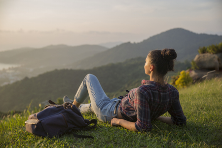 Hipster young girl with backpack enjoying sunset on peak mountain. Tourist traveler on background valley landscape view mockup.の写真素材