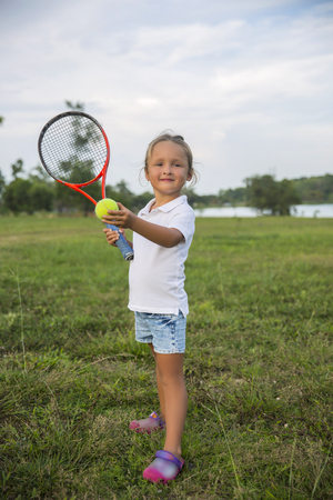 Sport kids girl with racket and ball. Child tennis player.の写真素材