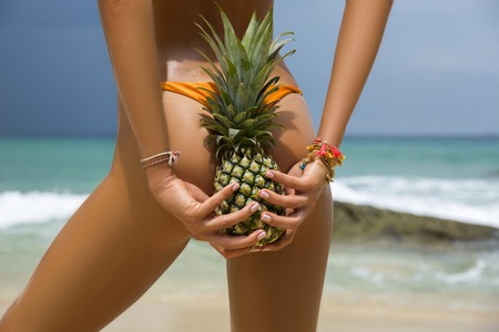 Sporty back of a beautiful woman in bikini with a seashell in her hands on sea background with copyspace. Sexy buttocksの写真素材