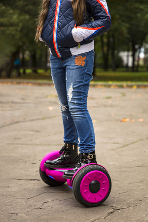 Child on hover board. Kids riding scooter in park. Balance board for children. Electric self balancing scooter on city street. Girl learning to ride hoverboard. Modern gadgets for school kid.の写真素材