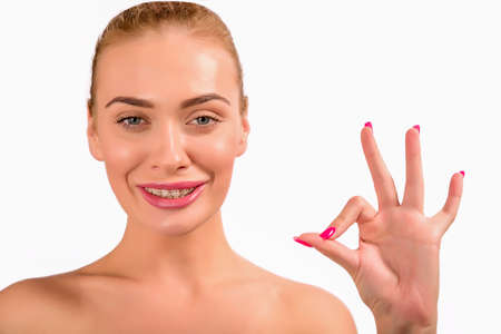 Braces. Beautiful Woman smile and showing an OK sign close up. Healthy Smile. Closeup Ceramic Braces...