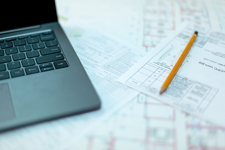Pencil and computer laptop on architectural drawing paper for constructionの写真素材