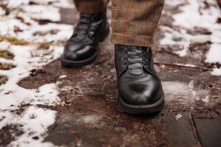Female feet in black boots, winter walking in snowの写真素材