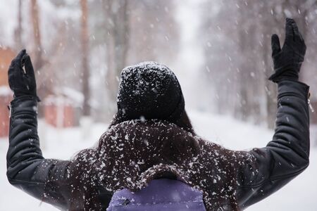 Cute young woman playing with snow in fur coat outdoors