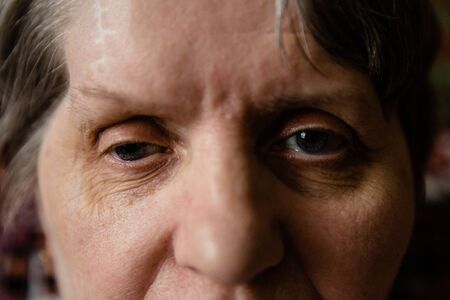 Retired woman with tired glance full of sadness looking away, extreme close-up shotの写真素材