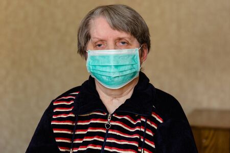 an elderly woman in a medical mask in quarantine and self-isolation, protecting the elderly from viruses and diseasesの写真素材