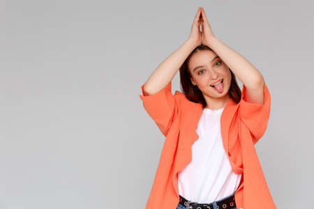 A young woman with long brown hair and a white t-shirt. purses her lips, makes a face, fooling around. Gesture. A childish woman plays the foolの写真素材