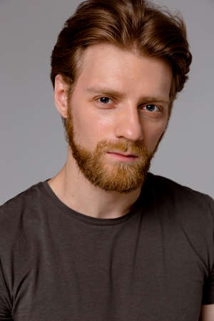 Close up portrait of fashionable redhead hipster man with fuzzy beard and trendy haircut wearing...