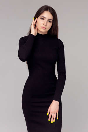 Beautiful woman standing in a black dress over gray backgroundの写真素材