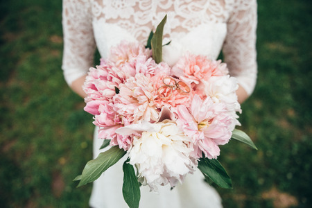Wedding bouquet of expensive fresh flowers in the hands of the brideの写真素材