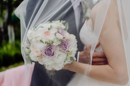 the groom hugs the bride by the waist, stand together under a white veil