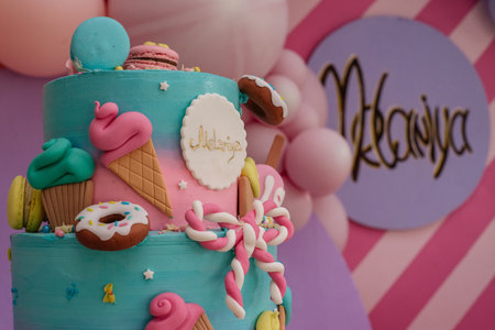 Bright colored handmade cake with edible, sweet decorative elements and macaroons for a children's...