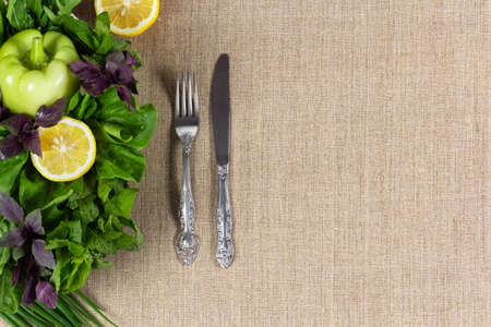 Green vegetables on the plate with fork and table knife on natural burlap backgroundの写真素材