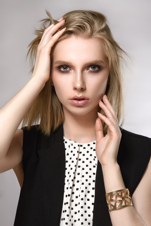 Beautiful blondekeeps hands near the face on the gray background. Concept of the beauty.の写真素材