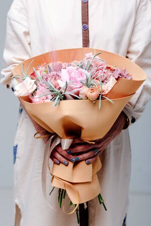 Bouquet of flowers in color of mustard foamiran package in the hands of a woman florist. Rose, carnation, lavender, ranunculus.の写真素材