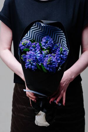 Bouquet of hyacinth flowers in black package in the hands of a woman florist.の写真素材
