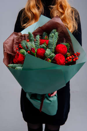 Bouquet of flowers in burgundy package in the hand of a woman florist on a blue background. Rosa, orchid, lily, brunia, carnation, eucalyptus.の写真素材