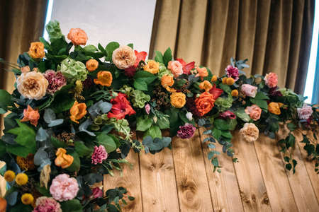 Fragment wedding presidium in restaurant. Wooden background with an arch of flowers and greeneryの写真素材
