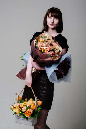 Portrait of young female florist brown-haired with a haircut with bouquets of flowersの写真素材