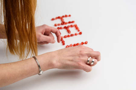 the word "hello" from pomegranate seeds on a white background with handsの写真素材