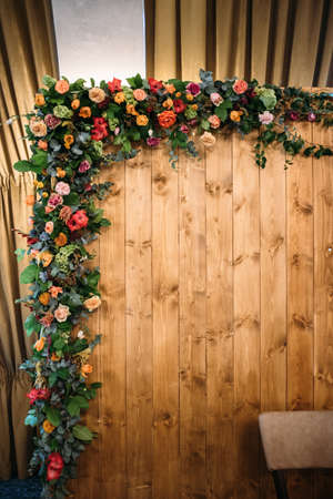 Fragment wedding presidium in restaurant. Wooden background with an arch of flowers and greeneryの写真素材