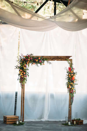 Wooden arch for the wedding ceremony, decorated cloth, flowers and greeneryの写真素材