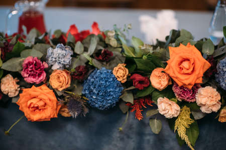 Wedding presidium in restaurant, free space. Wedding banquet table for newlyweds with flowers, greenery, blue velvet. Lush floral arrangement on wedding tableの写真素材