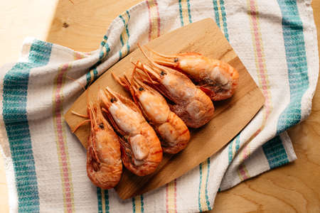 botan shrimp on a wooden board on a striped tableclothの写真素材