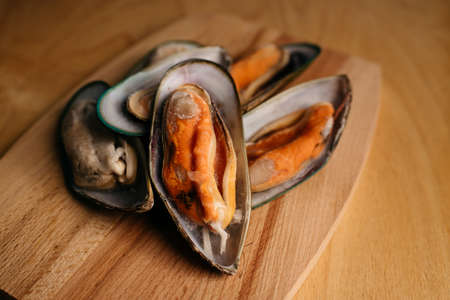 mussels in a shell on a wooden board on a wooden tableの写真素材