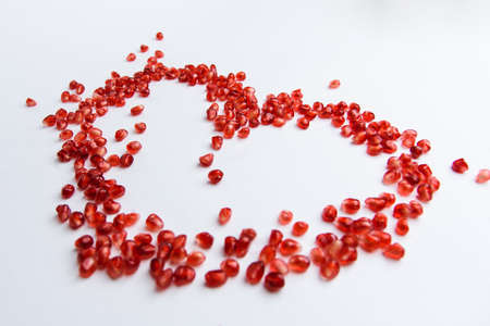 Heart symbol made from pomegranate seeds isolated on white backgroundの写真素材
