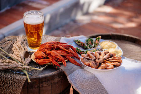 Boiled crayfish, beer, baked shrimp, baked mussels and scallops baked under cheese on a wooden barrelの写真素材