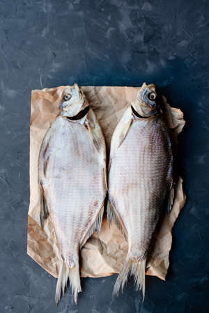 Two bream dried fish on craft paper on dark backgroundの写真素材
