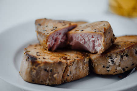 sliced fried tuna fillet in spices on a white plateの写真素材