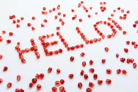 the word "hello" from pomegranate seeds on a white backgroundの写真素材