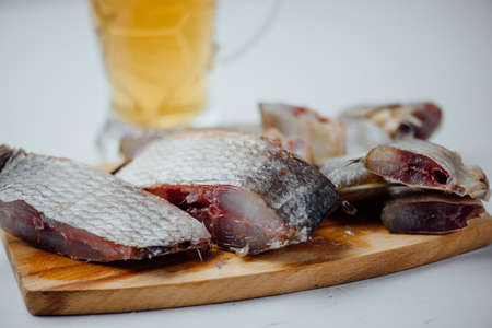 sliced salted fish on a wooden board and a glass of beer on a light backgroundの写真素材