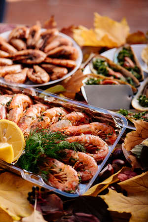 Fried shrimps and baked mussels on wooden table with autumn leaves and chestnuts.の写真素材