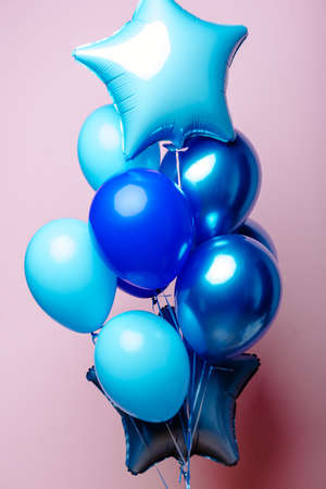 Composition of dark blue, blue, transparent helium balloons and two sapphirine star on a pink background.の写真素材