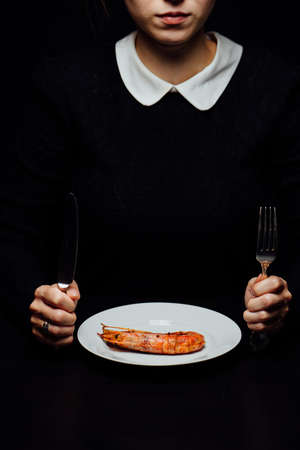 woman and fried lobster on a white plate with a knife and fork on a black backgroundの写真素材