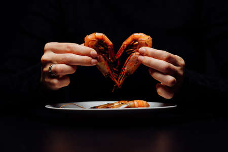 fried heart shaped shrimp in woman's hands on black backgroundの写真素材