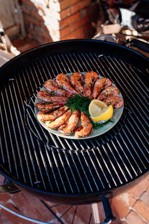 Fried shrimps with lemon and dill on white plate on background grillの写真素材