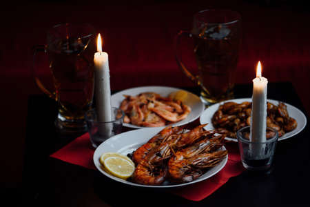 two candle two glass of beer, shrimps, lobsters, dark backgroundの写真素材