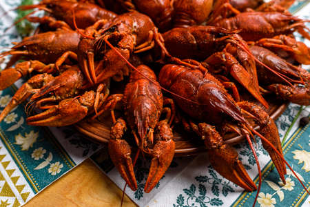 boiled crayfish on a plate on a blue tablecloth on a wooden tableの写真素材