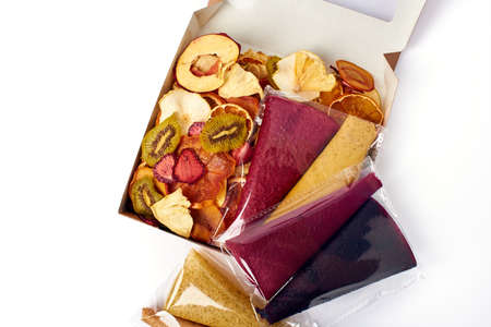 Mix dried fruits and mix fruit pastille marshmallow in open craft paper square box on white...