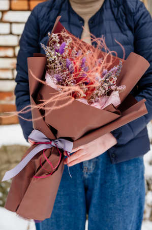 Beautiful bouquet of lavender, limonium and feather grass in brown packaging in hands of womanの写真素材