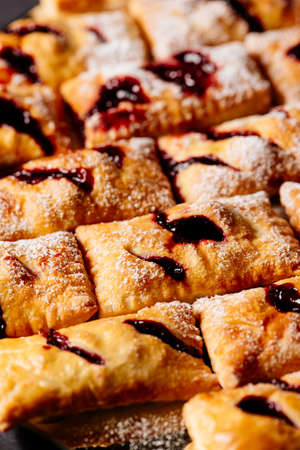 Sweet puff buns with jam sprinkled with powdered sugar on black backgroundの写真素材