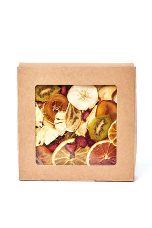 Mix dried fruits in craft paper square box with transparent lid on white background. Vegetarian lifestyle.の写真素材